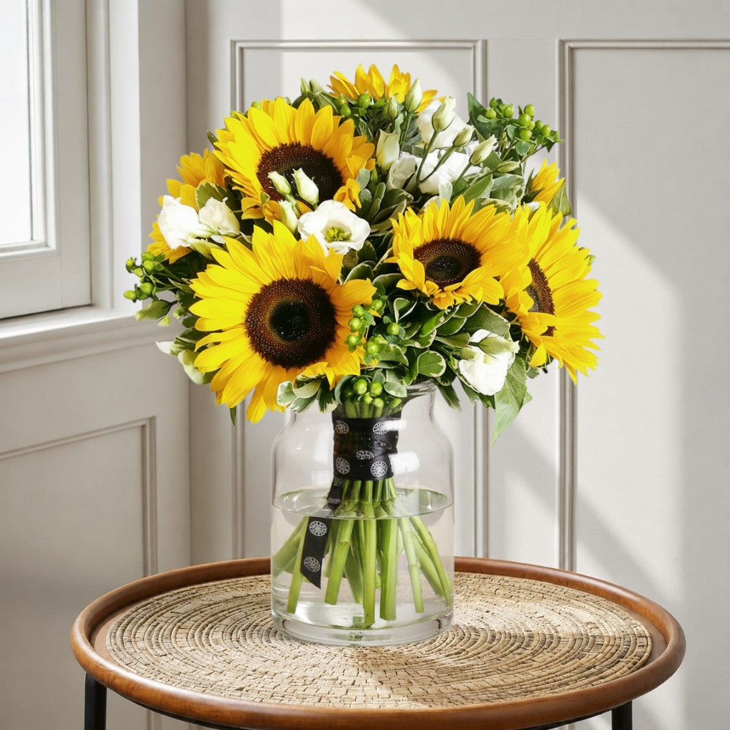 Flower Station bouquet featuring bright yellow sunflowers, white lisianthus, and green hypericum berries with pittosporum.